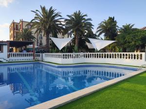 a swimming pool with palm trees and a white fence at Hotel San Martin in Altafulla