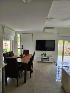 a dining room with a table and chairs and a television at Reef Terraces on St Crispins - Villa 2 in Port Douglas