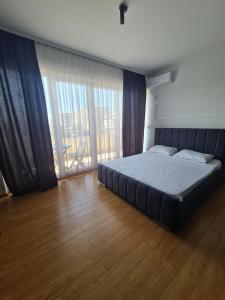 a large bed in a room with a large window at Apartment 1 Plisi Gjilan in Gjilan