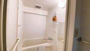 a white bathroom with a tub and a sink at Esperanza 204号室 in Tokyo