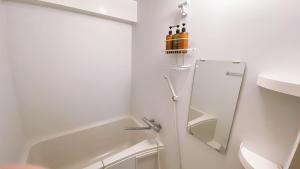 a white bathroom with a tub and a mirror at Esperanza 204号室 in Tokyo
