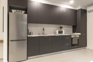 eine Küche mit schwarzen Schränken und einem Kühlschrank aus Edelstahl in der Unterkunft Apartamento Bronce by Clabao in Madrid