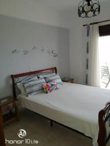 a bedroom with a white bed with pillows and a window at Avra Ηouse in Kriopigi