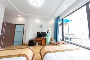 a woman standing in a bedroom with two beds at Homestay SUNA Tuy Hòa, Phú Yên in Tuy Hoa