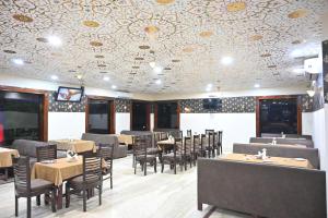 奥拉奇哈Orchha Club and Resort - OCR的一间有桌椅和带图案的天花板的餐厅