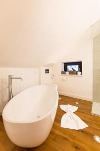 y baño con bañera blanca y suelo de madera. en Raffl's Sweet Little Home, en Sankt Anton am Arlberg