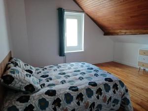 a bedroom with a comforter on a bed with a window at Gite du Bois Rosé in Fécamp
