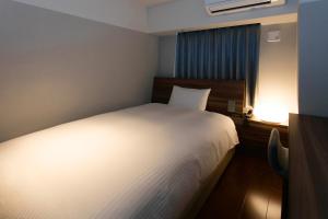 a bedroom with a white bed and a lamp at BRENZA HOTEL in Kobe