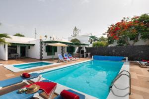 a swimming pool with chairs and a house at Villa Mirafondo in Tías