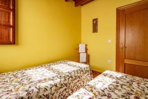 two beds in a room with yellow walls at Comeya in Cangas de Onís
