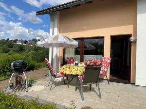 a patio with a table and chairs and an umbrella at Berghof Arnika in Sankt Andreasberg