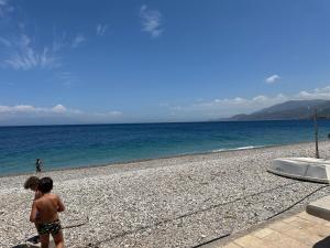 Un niño pequeño parado en una playa rocosa en Ένα διαμάντι στην Ακράτα, en Paralía Akrátas