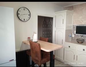 a dining room with a table and a clock on the wall at Maison village en Aveyron in Durenque