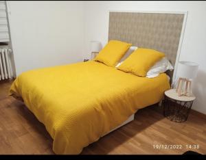 a yellow bed with yellow sheets and pillows at Maison village en Aveyron in Durenque +4 photos
