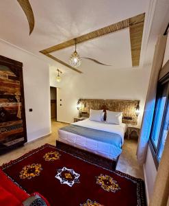 a bedroom with a large bed and a red rug at Dar Rihana Dadès in Aït Idaïr