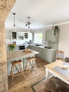 a kitchen with white cabinets and a table and chairs at Kionslieu Farm Cottages in Foxdale