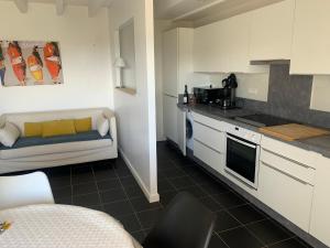 a kitchen with white cabinets and a couch in a room at LE CAP in Erquy +9 photos