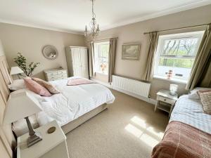 a bedroom with two beds and a chandelier at Kionslieu Farm Cottages in Foxdale