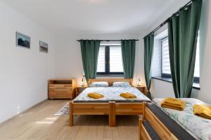 two beds in a room with green curtains at Apartments Žiar 114 in Žiar +18 photos