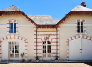a large white house with two garage doors at Maison Adrienne in Saint-Aignan