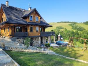 una casa de madera con un parque infantil delante de ella en Villa Ligęzówka, en Chyrowa