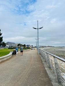 two people walking down a path next to the beach at The South Promenade apartment in Newcastle +10 photos