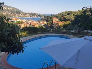 ein blauer Swimmingpool mit einem weißen Sonnenschirm daneben in der Unterkunft La Palma in Lerici