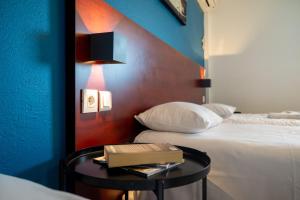 Initial by Balladins Lyon Villefranche-sur-Saône في فيلفرانش سور سون: غرفة بسريرين وطاولة مع كتاب