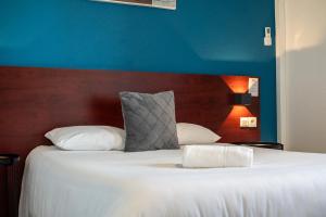 Un dormitorio con una cama grande con una pared azul. en Initial by Balladins Lyon Villefranche-sur-Saône, en Villefranche-sur-Saône