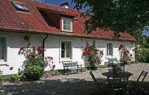 奇维克Stenrosgården的一座有红色屋顶、椅子和鲜花的白色房子