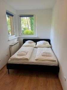 two beds in a small room with two windows at Letni domek na wydmie in Pobierowo