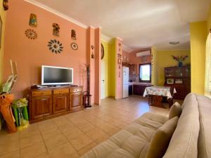 a living room with a couch and a flat screen tv at Casa con giardino con climatizzatore!!! in Costa Rei