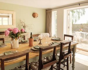 a dining room with a wooden table with chairs at Vine Cottage in Shepton Mallet