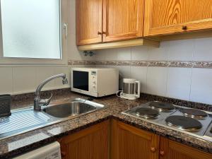 eine Küche mit Spüle und Mikrowelle in der Unterkunft Homely Apartments Sol Y Mar in Torrevieja + 44 Fotos