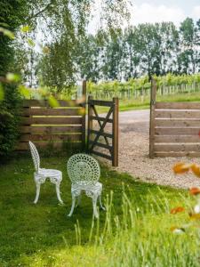 two chairs sitting in the grass next to a fence at Vine Cottage in Shepton Mallet