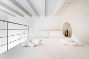 a white bedroom with a large white bed with two pillows at LUVI - Pietro Custodi in Milan