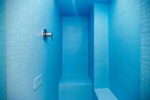 a blue bathroom with a shower with a blue wall at LUVI - Pietro Custodi in Milan