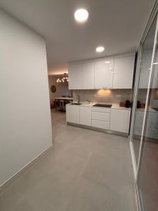 an empty kitchen with white cabinets and a table at Apartamento Olimpic Beach in Roquetas de Mar