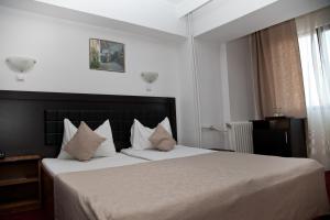 a bedroom with a large bed with white sheets and pillows at Hotel Metropol in Piteşti