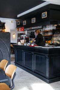 a woman preparing food at a bar in a restaurant at Hotel Reine Mathilde in Bayeux