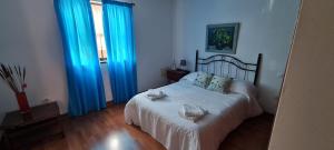 a bedroom with a white bed with blue curtains at Mgrahamhouse in Tacoronte