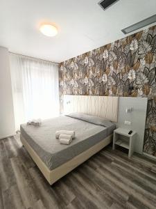 a bedroom with a large bed with a floral wallpaper at Residence Hotel Angeli in Rimini