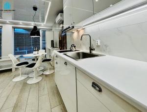 a kitchen with white cabinets and a sink and a table at Pod Brzozami Apartamenty Gąski in Gąski +121 photos