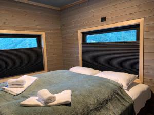 a bedroom with two towels on a bed with two windows at Stryn Golden Resort - Panorama II in Stryn