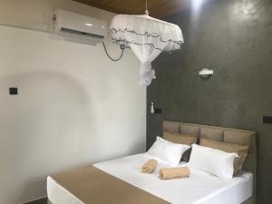 a bedroom with a bed with white sheets and a chandelier at Flip Flop Inn Mirissa in Mirissa