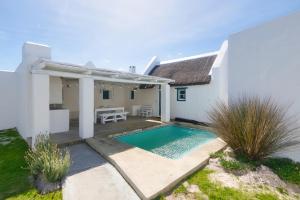 una villa con piscina di fronte a una casa di Skulpies Cottage Langezandt In Struisbaai a Struisbaai