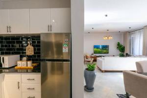 a kitchen with a stainless steel refrigerator and a living room at Serenita Homes Arusha in Arusha
