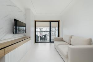 ein weißes Wohnzimmer mit einem Sofa und einem Fenster in der Unterkunft Nowoczesny Apartament Przy Plaży z Parkingiem by Noclegi Renters in Ustronie Morskie