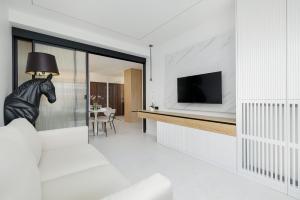 ein Wohnzimmer mit einem weißen Sofa und einem Fernseher in der Unterkunft Nowoczesny Apartament Przy Plaży z Parkingiem by Noclegi Renters in Ustronie Morskie