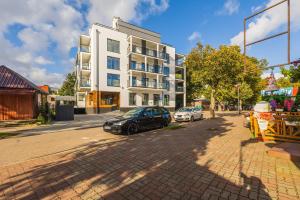 eine Straße mit vor einem Gebäude geparkten Autos in der Unterkunft Nowoczesny Apartament Przy Plaży z Parkingiem by Noclegi Renters in Ustronie Morskie